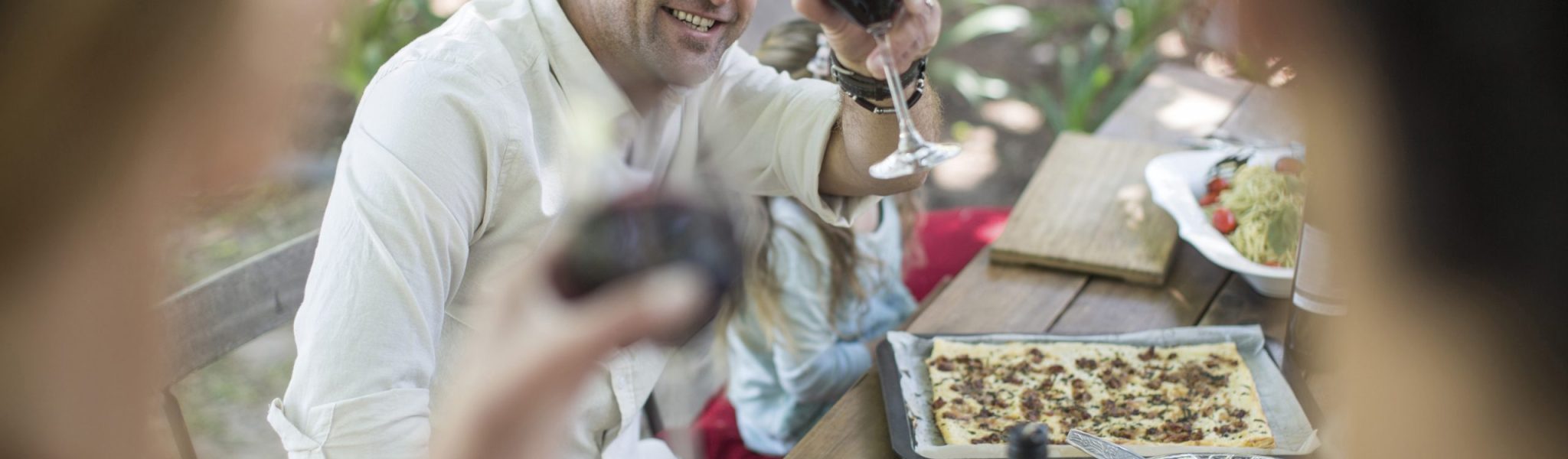 Friends and family having lunch in garden with red wine